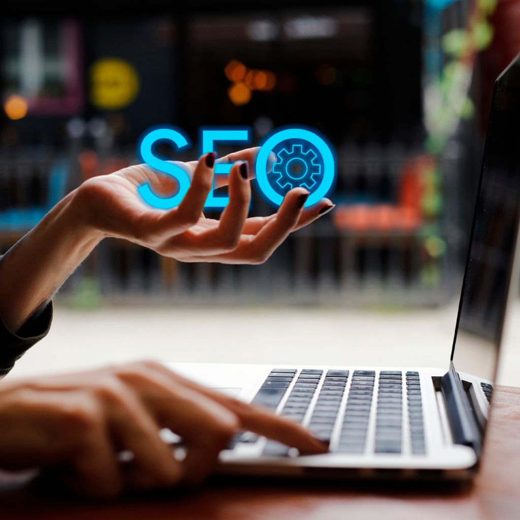 Mãos operando um computador com ícone holográfico de SEO e engrenagem, simbolizando o processo técnico de Auditoria de SEO no Site